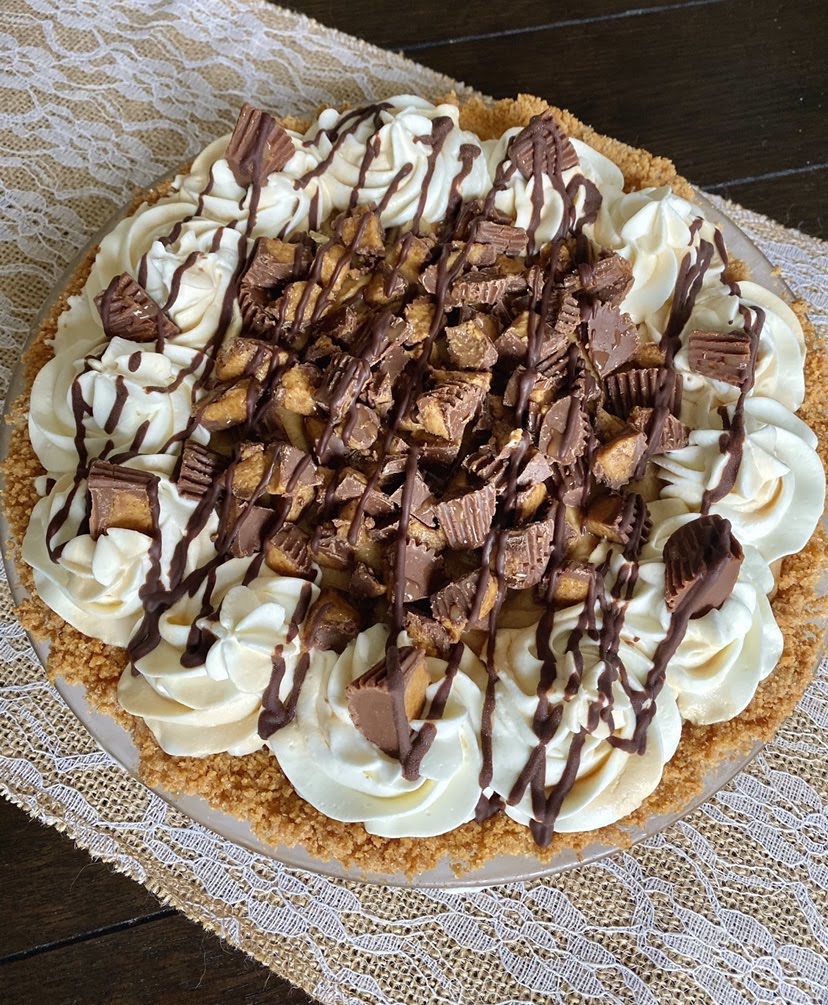 overhead view of chocolate peanut butter pie toped with chocolate drizzle, whipped cream, and Reese's cups