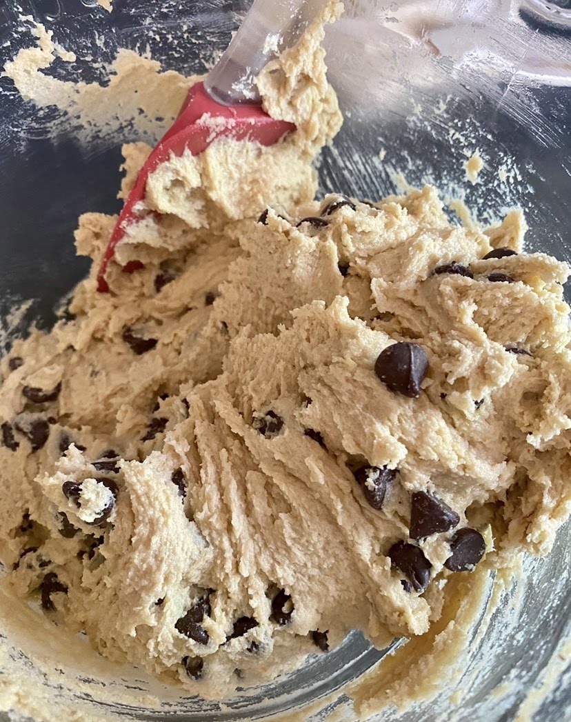 Chocolate chip cookie cake dough in a glass mixing bowl.