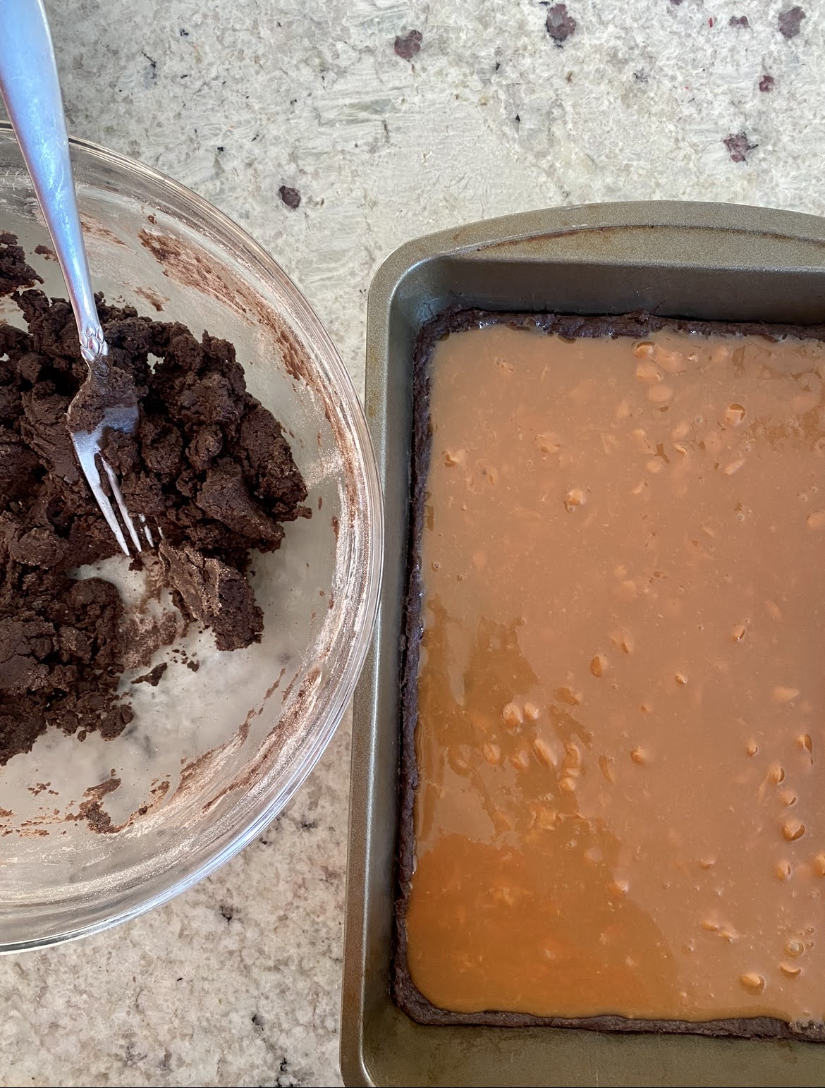 the melted caramel layer over the baked chocolate layer, and the remaining chocolate dough in a bowl. 