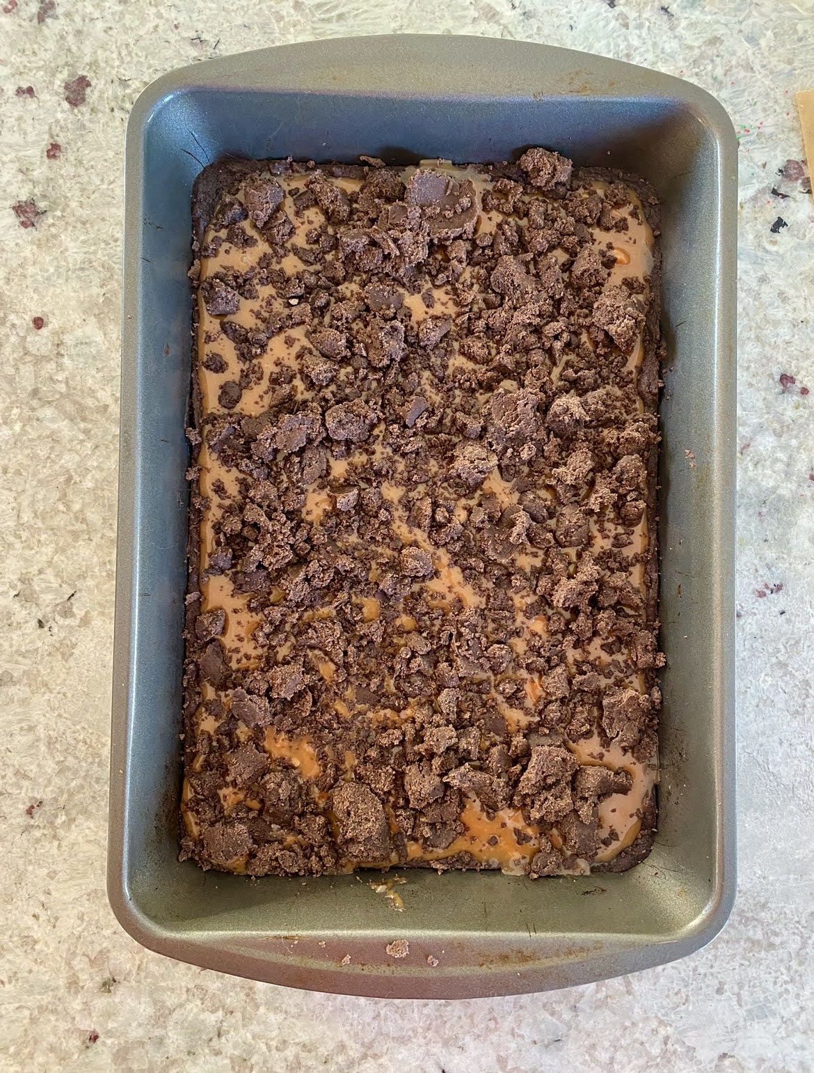the remaining chocolate dough sprinkled over the caramel layer in a baking pan