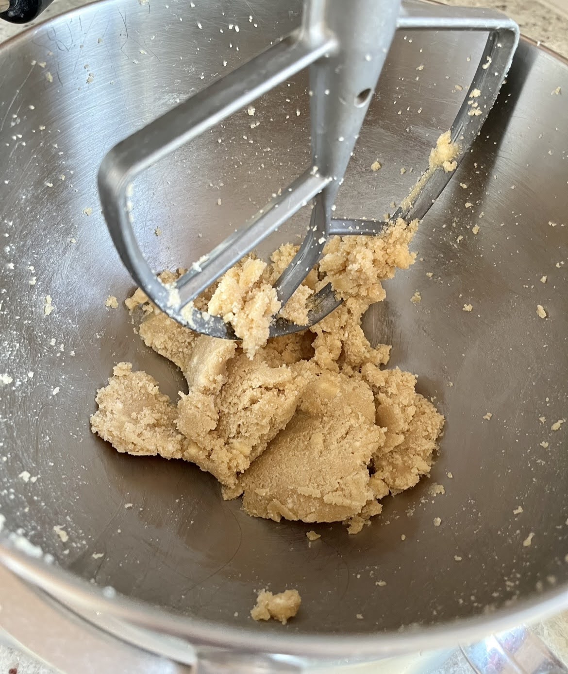 Butter and sugar being creamed in the silver bowl of a stand mixer. 