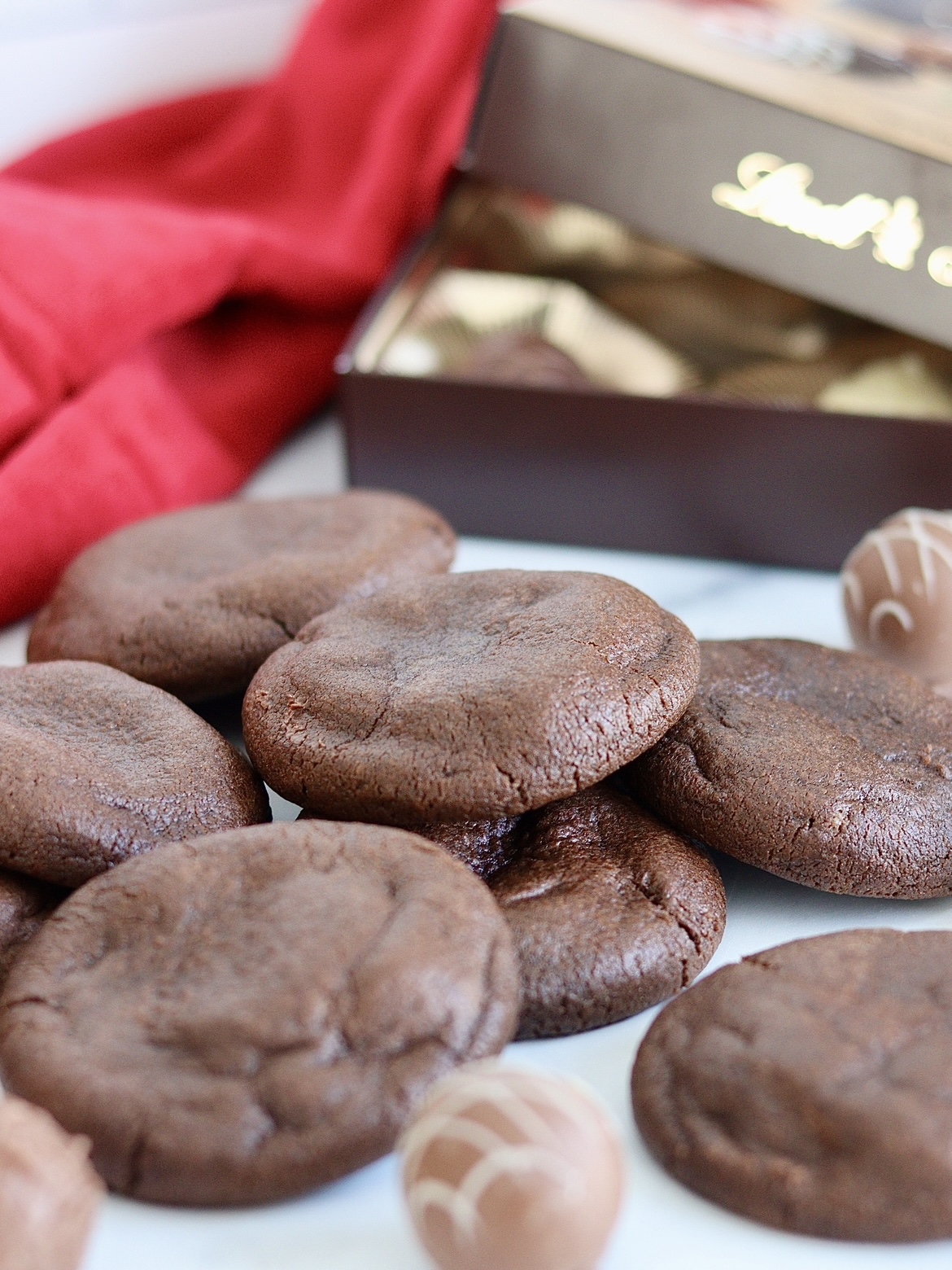 chocolate cookies with an open box of chocolate truffles behind them to show chocolate truffle filling