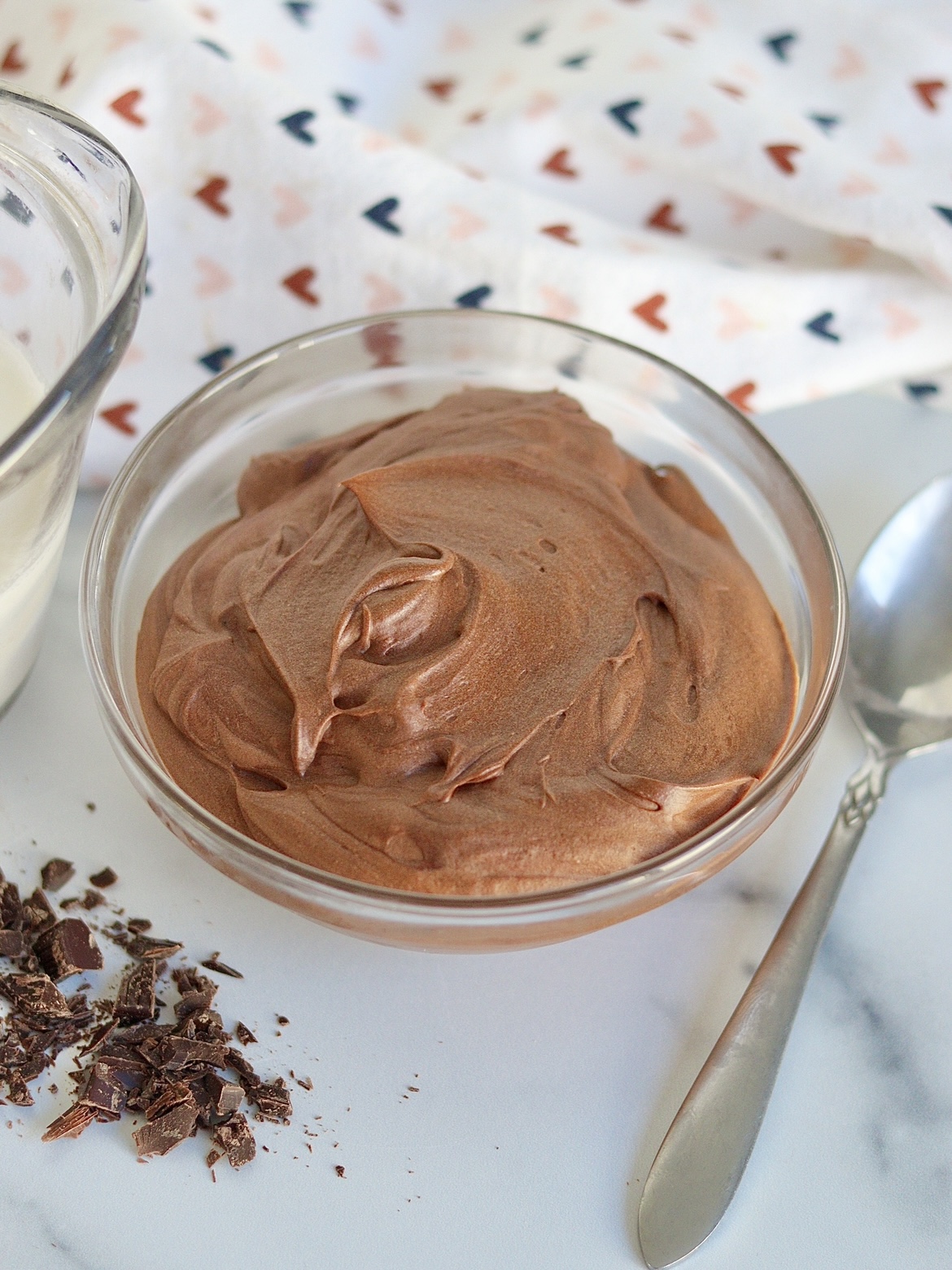 A bowl of two ingredient chocolate mousse with its ingredients next to it (heavy cream and chocolate shavings)
