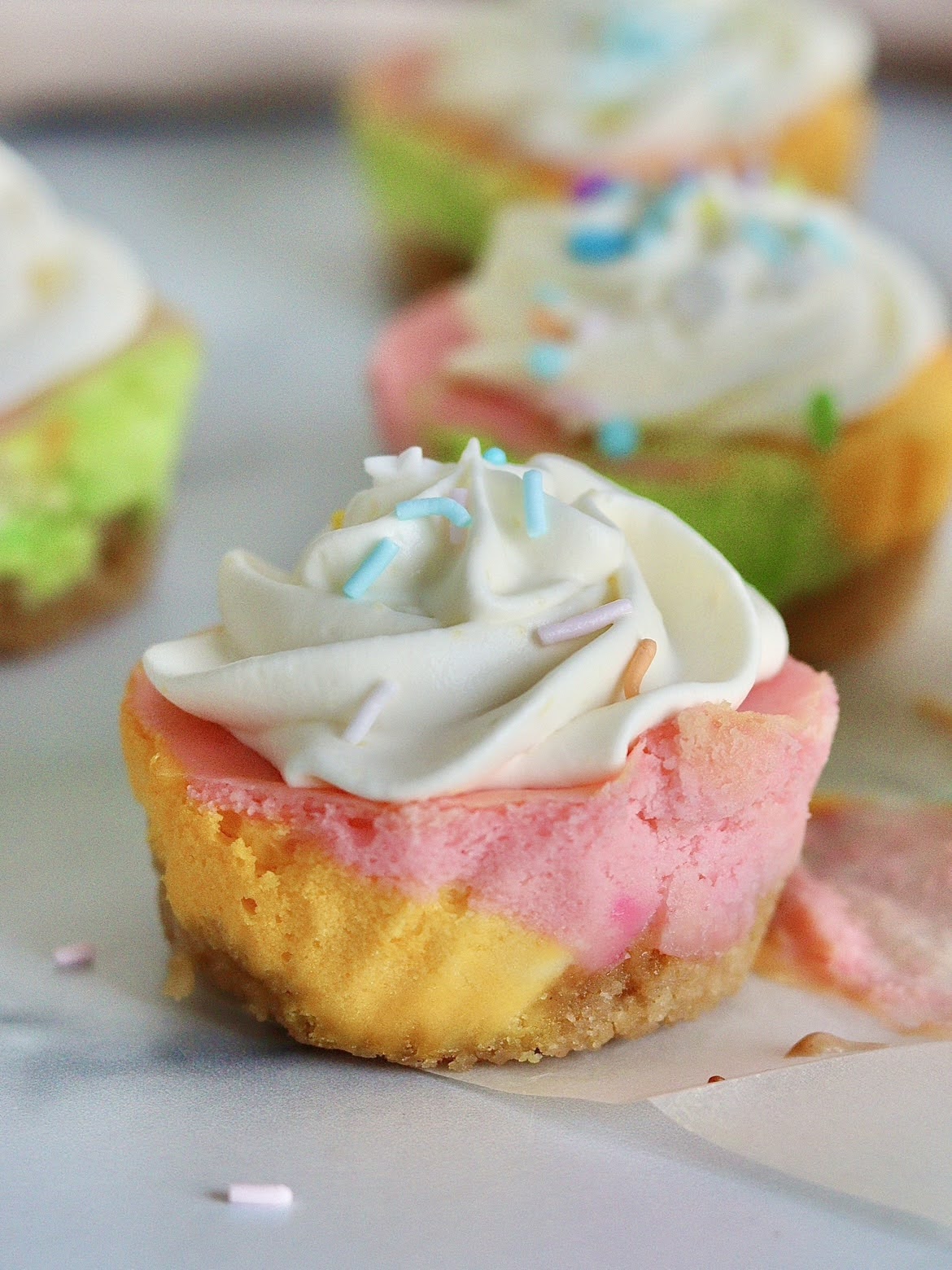 one mini unicorn cheesecake topped with a swirl of whipped cream and sprinkles