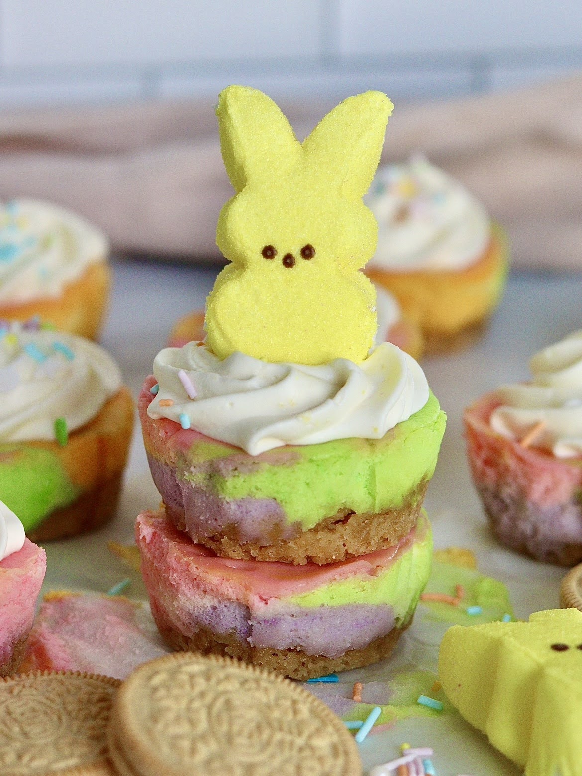 stacked mini unicorn cheesecakes, topped with whipped cream and a peep