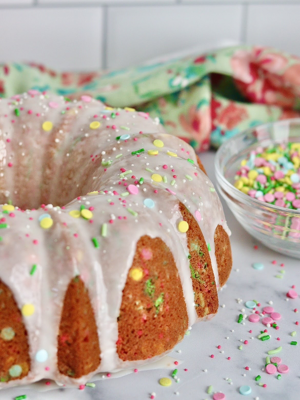 An full sprinkle bundt cake covered in icing and sprinkles