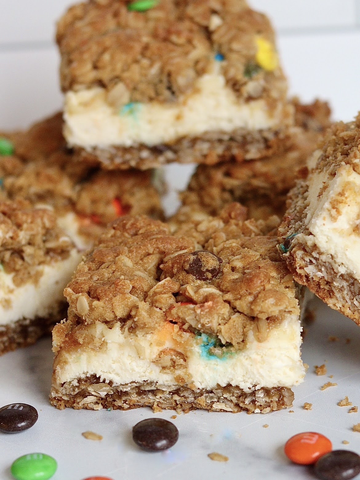 A close up view of a slice of a monster cookie cheesecake bar