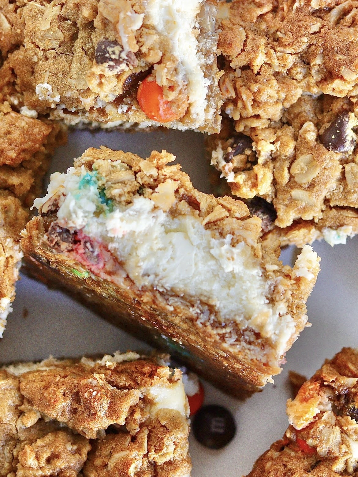 Overhead view of a monster cookie cheesecake bar on its side, showcasing the crust, cheesecake and cookie layer