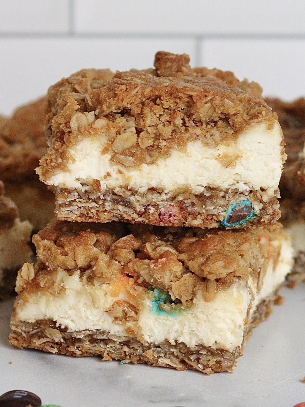 Two monster cookie cheesecake bars stacked on top of each other