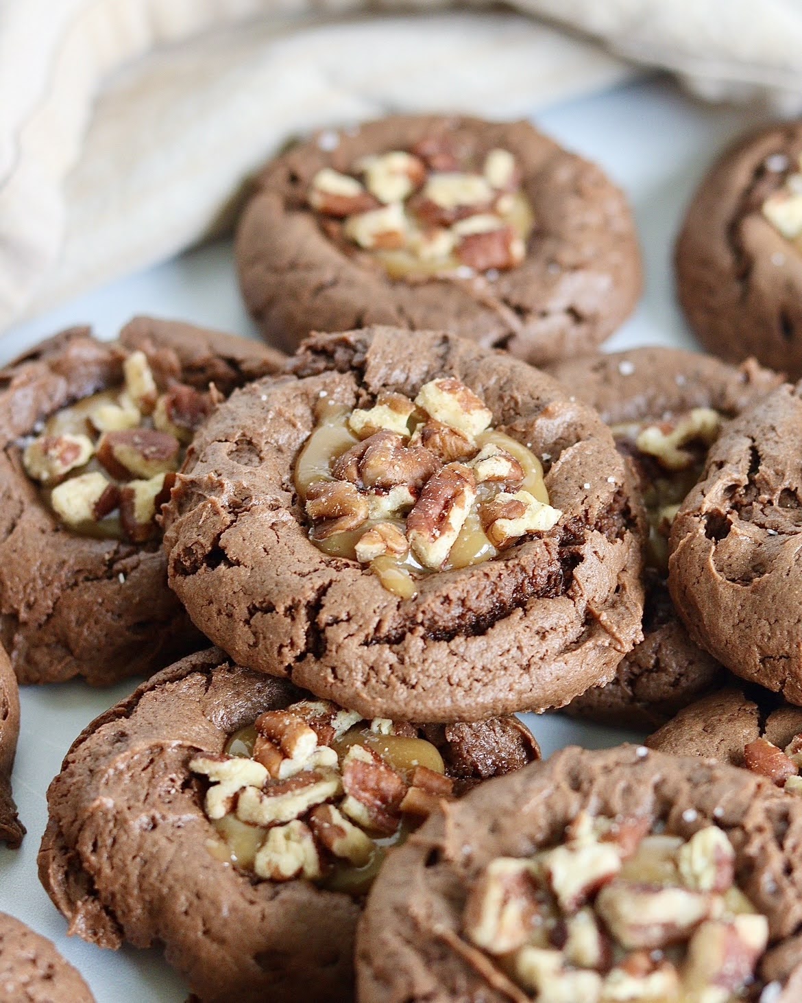 a close up photo of chocolate turtle thumbprint cookies