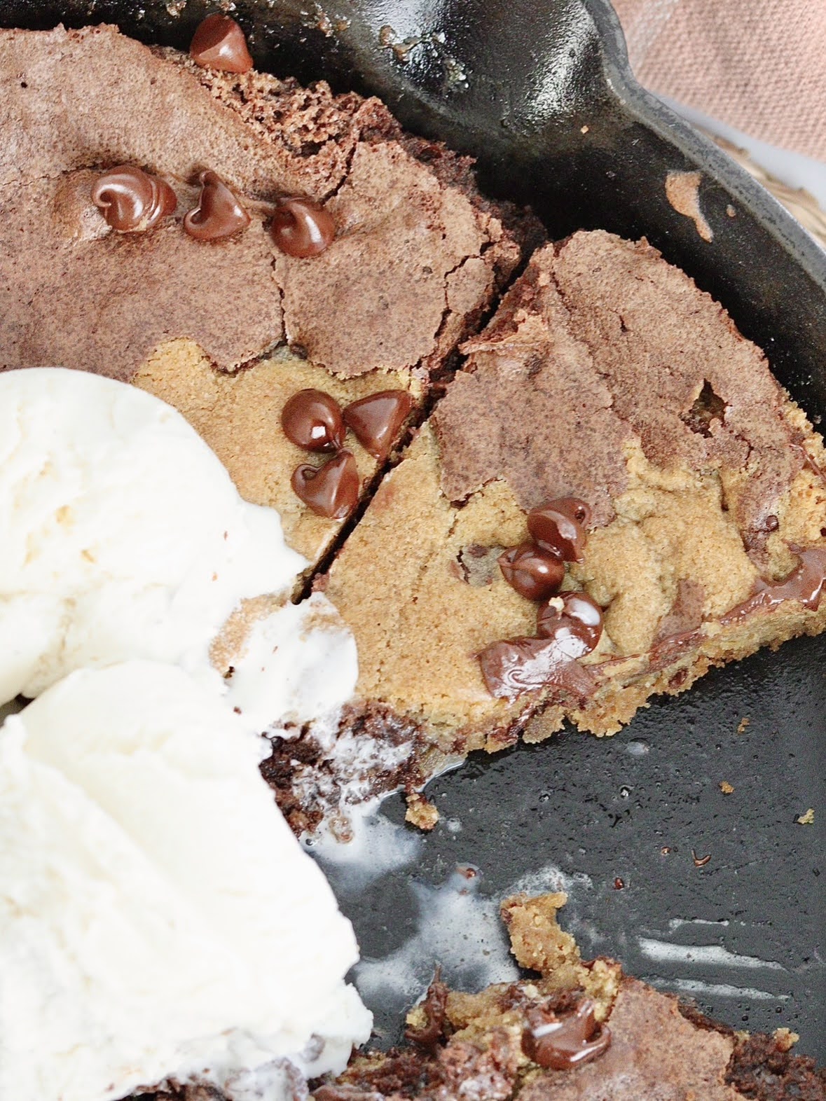 Close up photo of a warm skillet brookie, topped with melting ice cream.