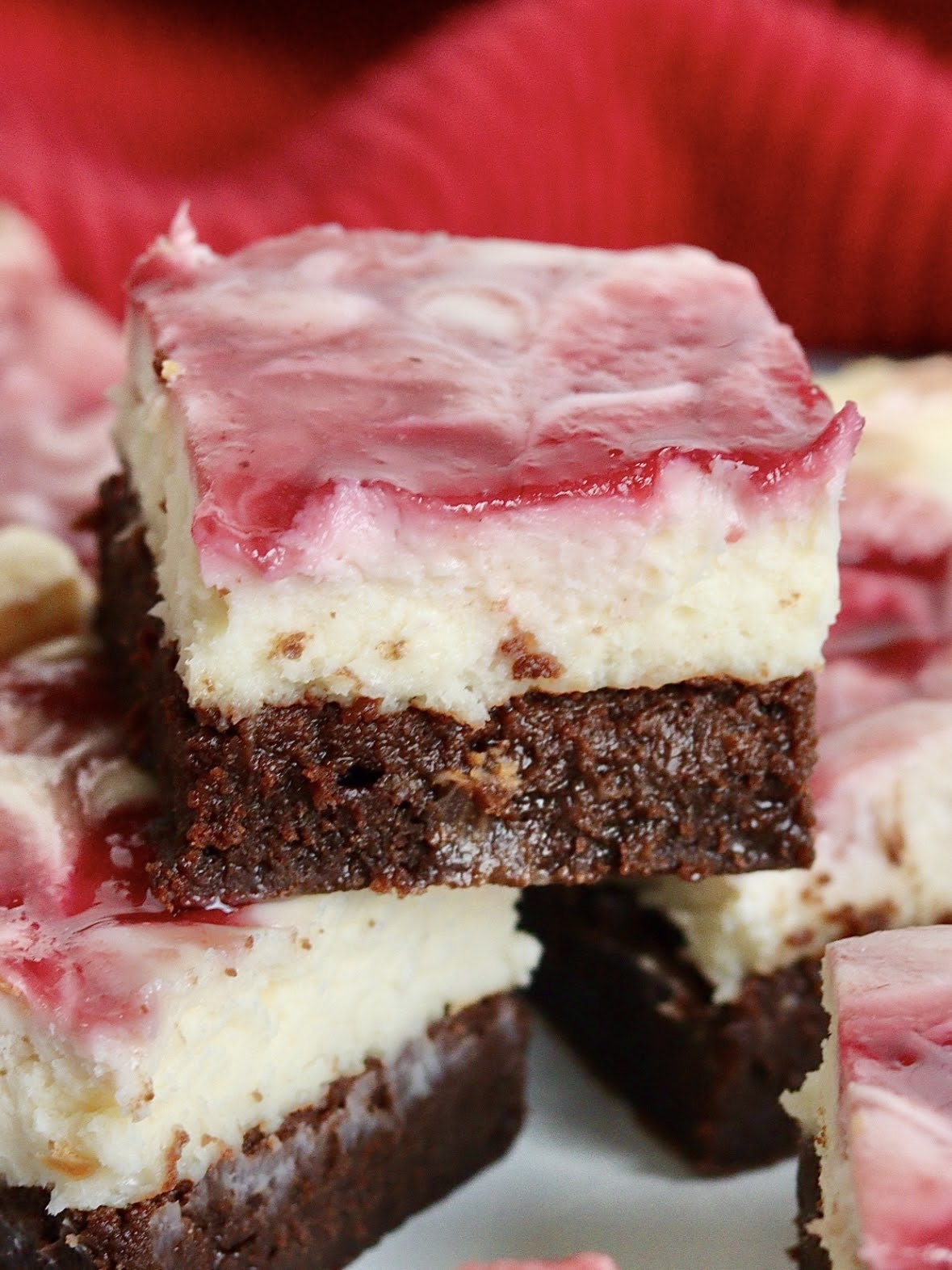 a piece of raspberry cheesecake brownie on top of other slices