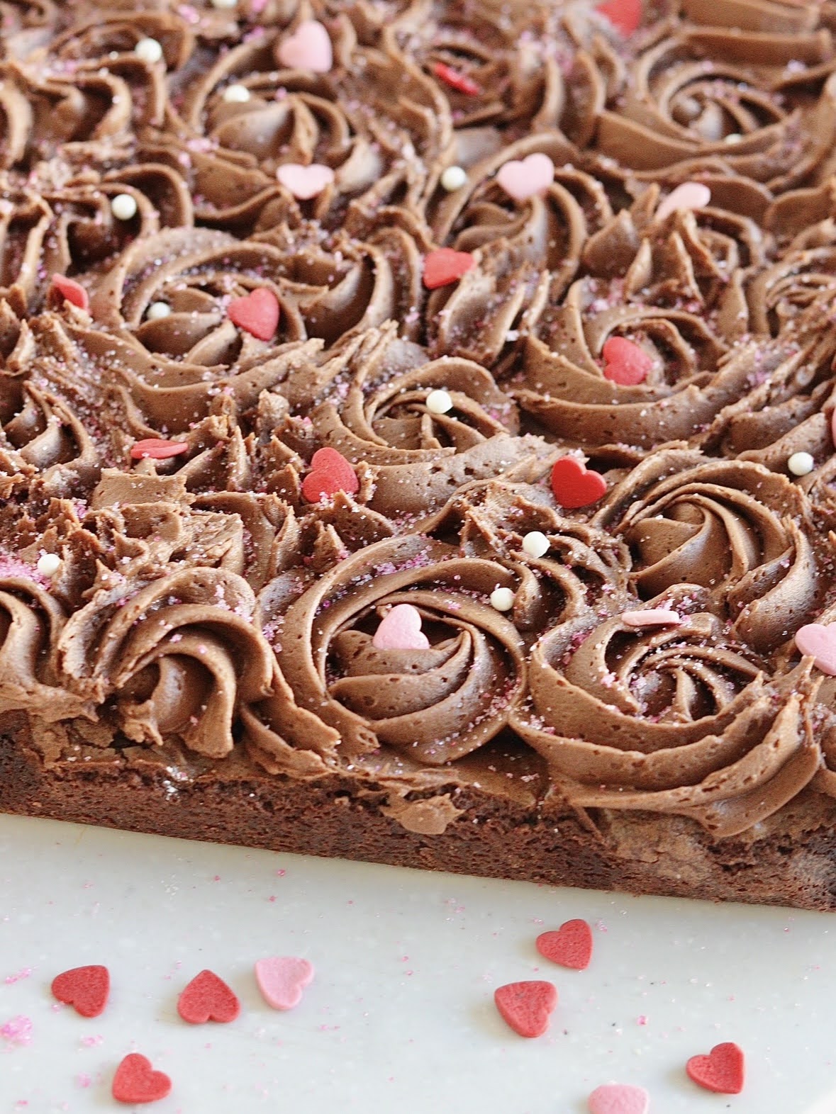 close up photo of the heart shaped frosted brownie, showcasing the chocolate frosting swirls and sprinkles