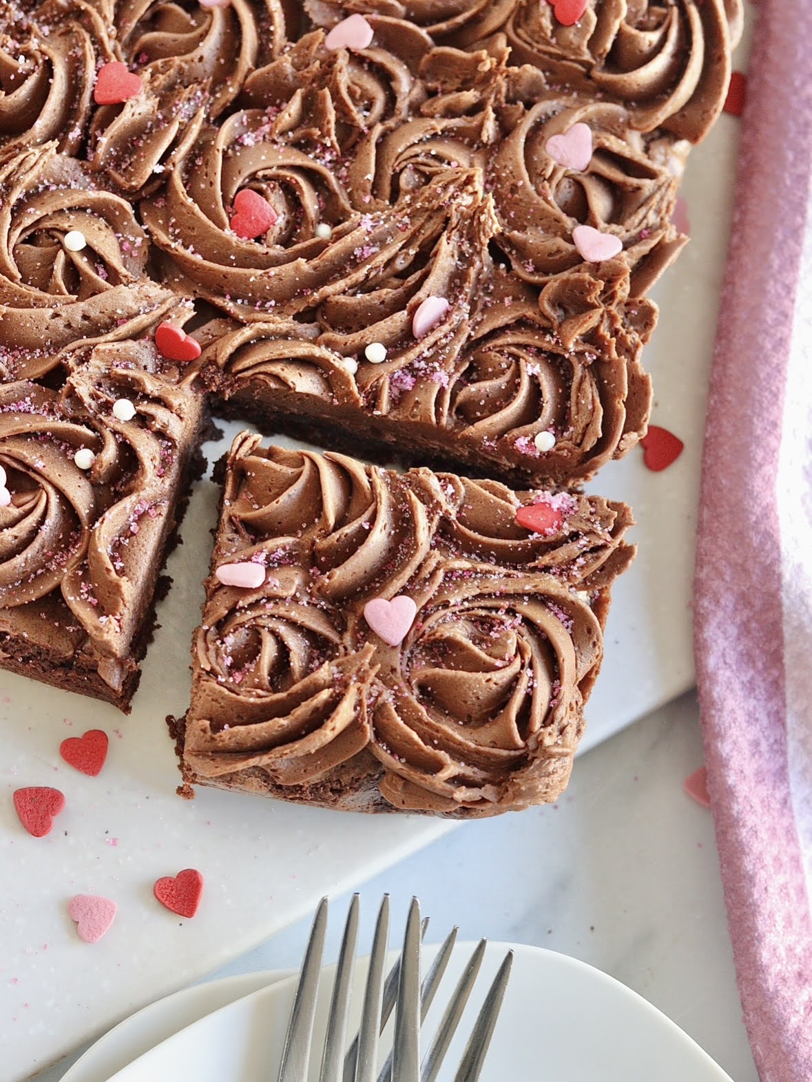 slice of frosted brownie with a plate and forks next to it