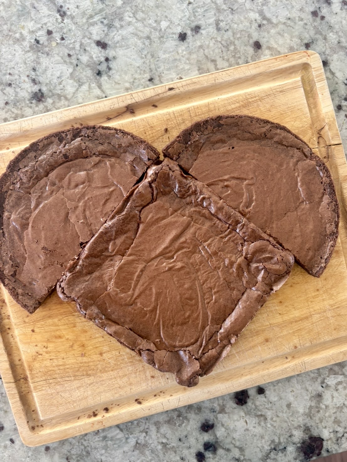 process photo of the heart brownie assembly, showing the 9x9-inch square brownie with the round brownie halved and placed at the top of the square brownie to begin to shape it into a heart