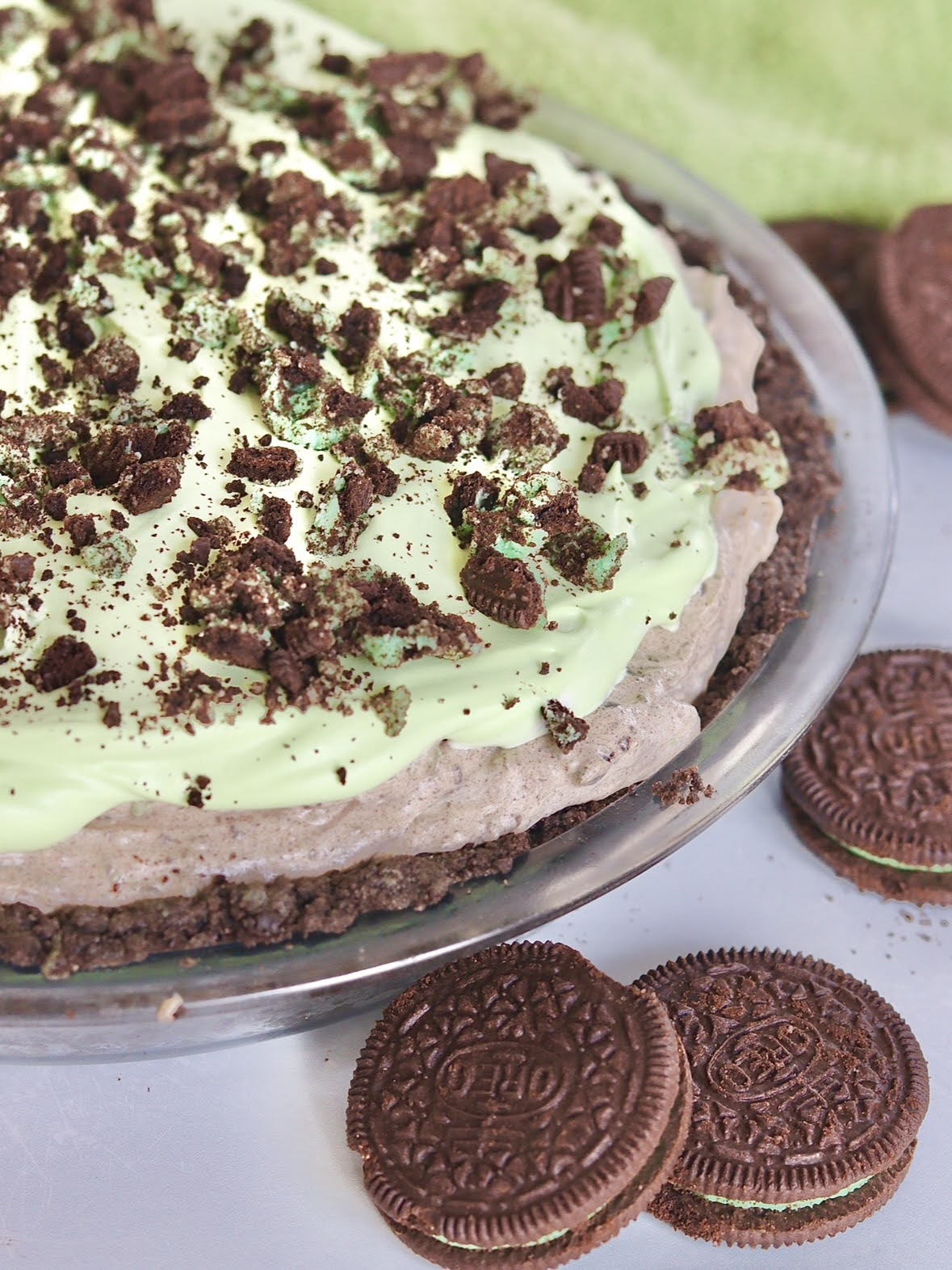 Close up photo of a mint Oreo Truffle pie, topped with crushed mint oreo's and green whipped cream.