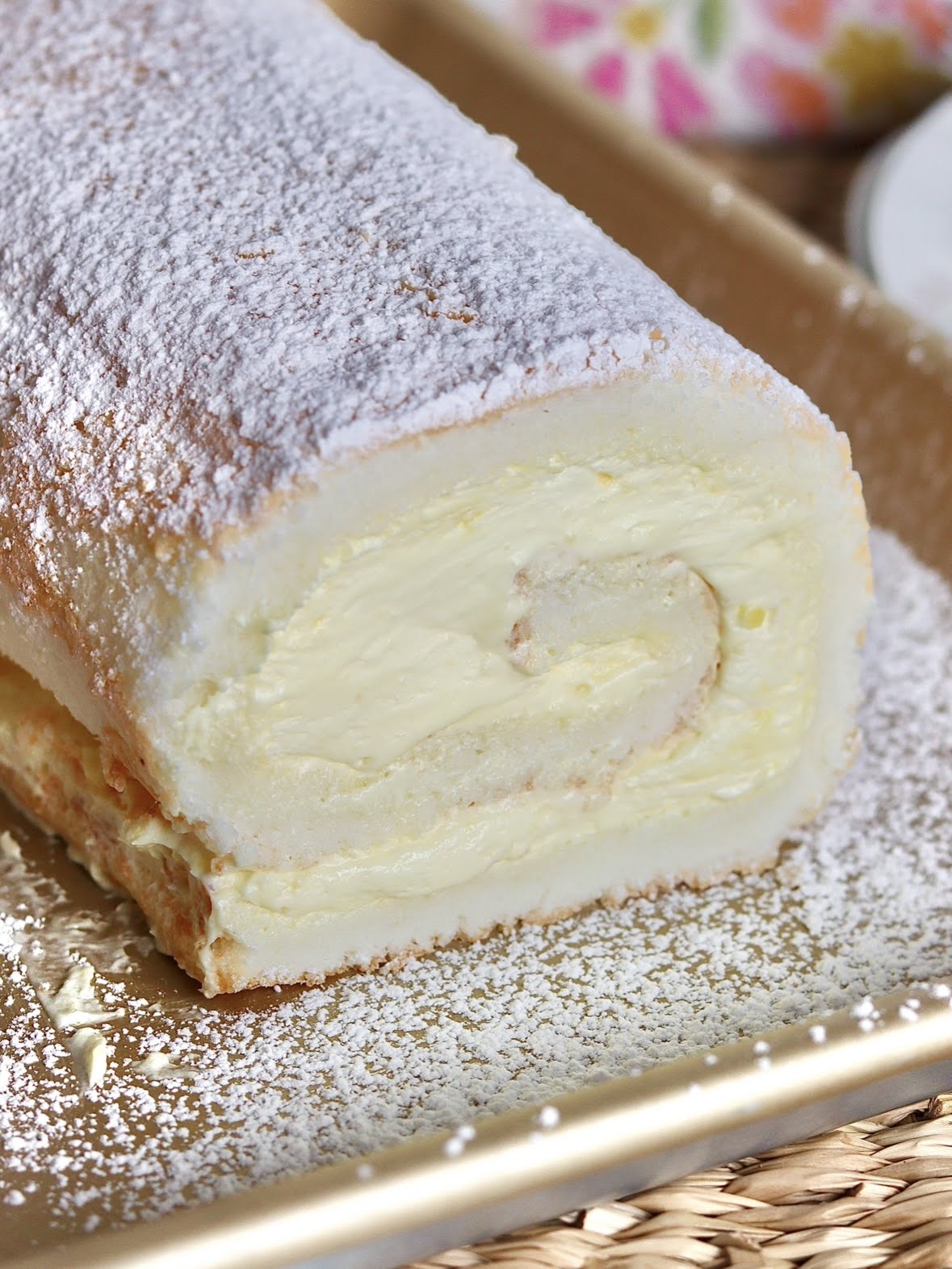 close up photo of a sliced lemon angel food cake roll, covered in powdered sugar