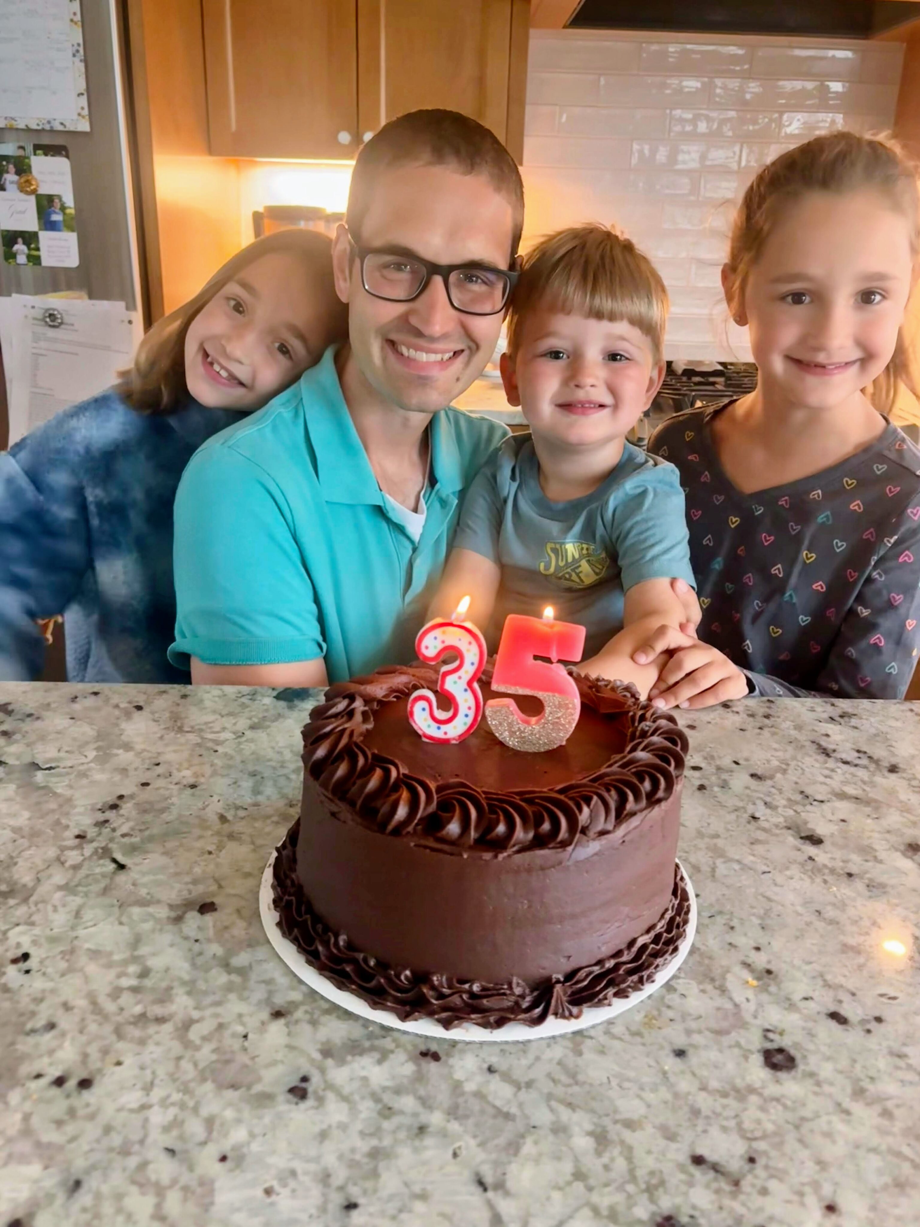 A photo of my family with the chocolate cake and candles in the shape of a 3 and 5.
