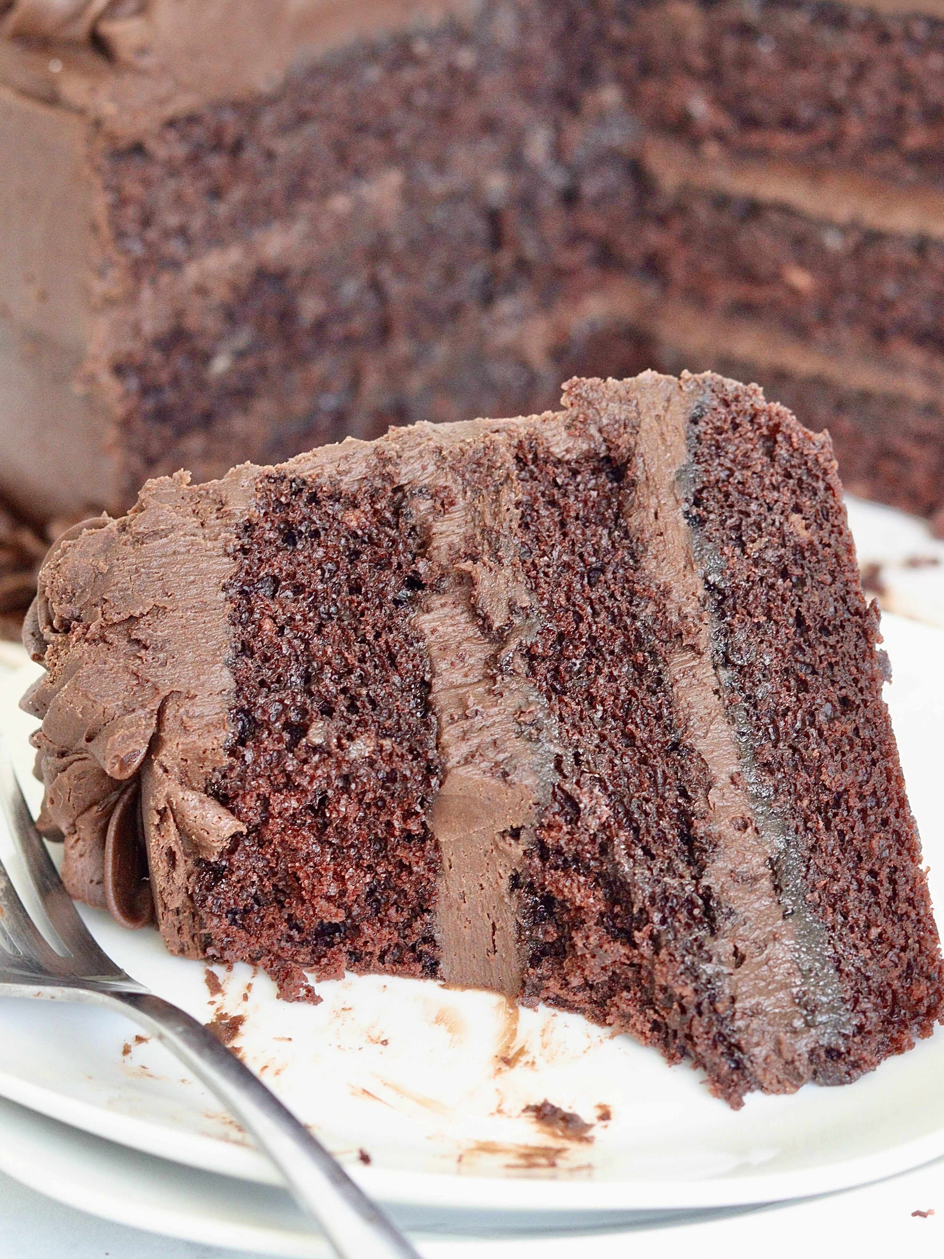 A slice of chocolate layer cake with a bite taken out of it.
